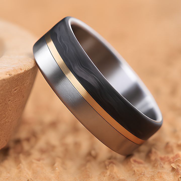 Titanium wedding ring with forged carbon fiber and a thin brass inlay on a tan background