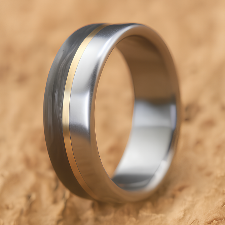 Titanium and carbon fiber wedding ring with brass accent, standing upright on a beige surface