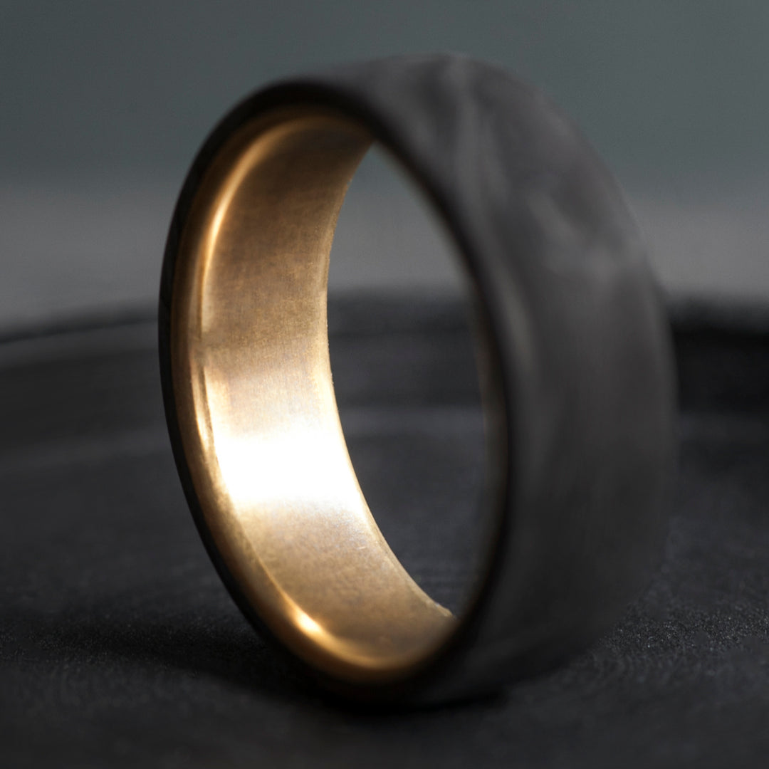 Domed forged carbon fiber ring with golden brass core and organic black grain pattern