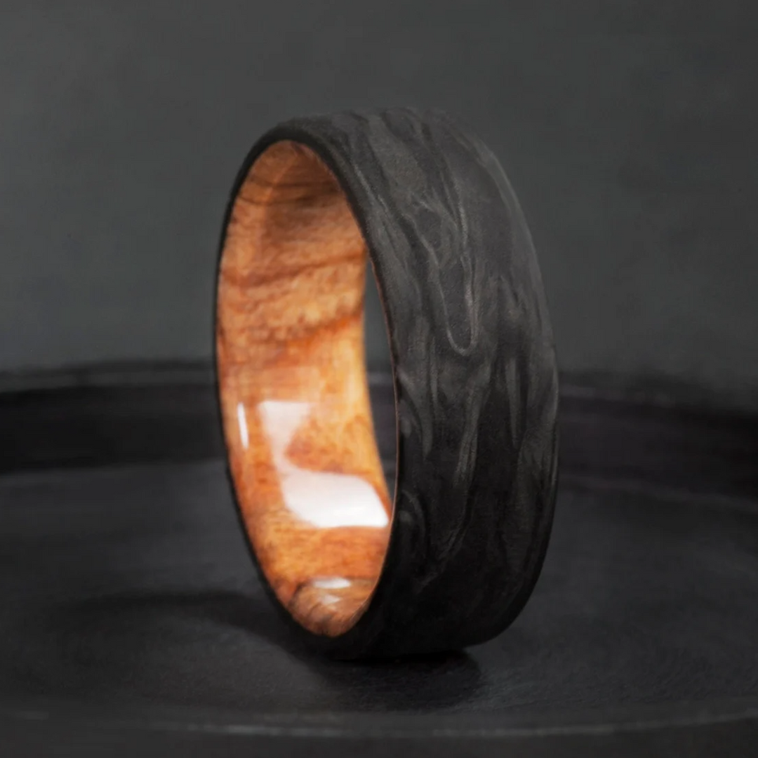 This spalted maple wood wedding ring holds a pale, black-lined interior inside a forged carbon fiber shell. 
