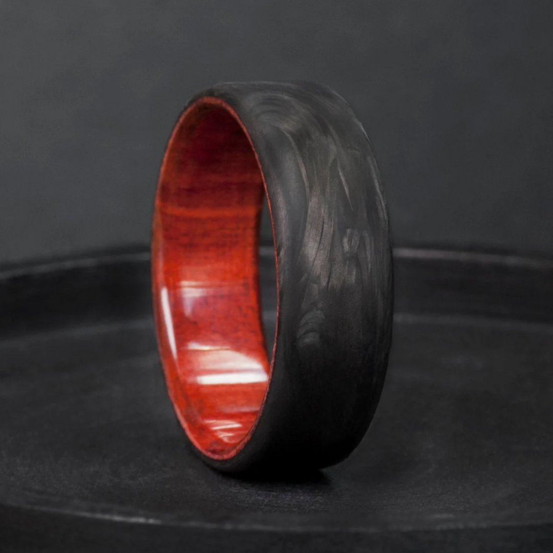 Anniversary ring built around a crimson redheart wood interior and a forged carbon fiber exterior