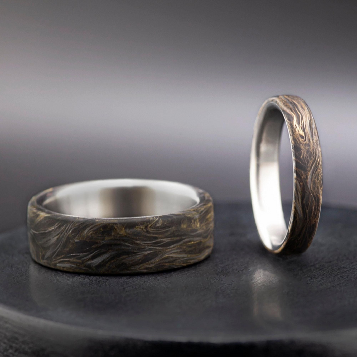 Handcrafted titanium and carbon fiber wedding band with swirling gold leaf accents